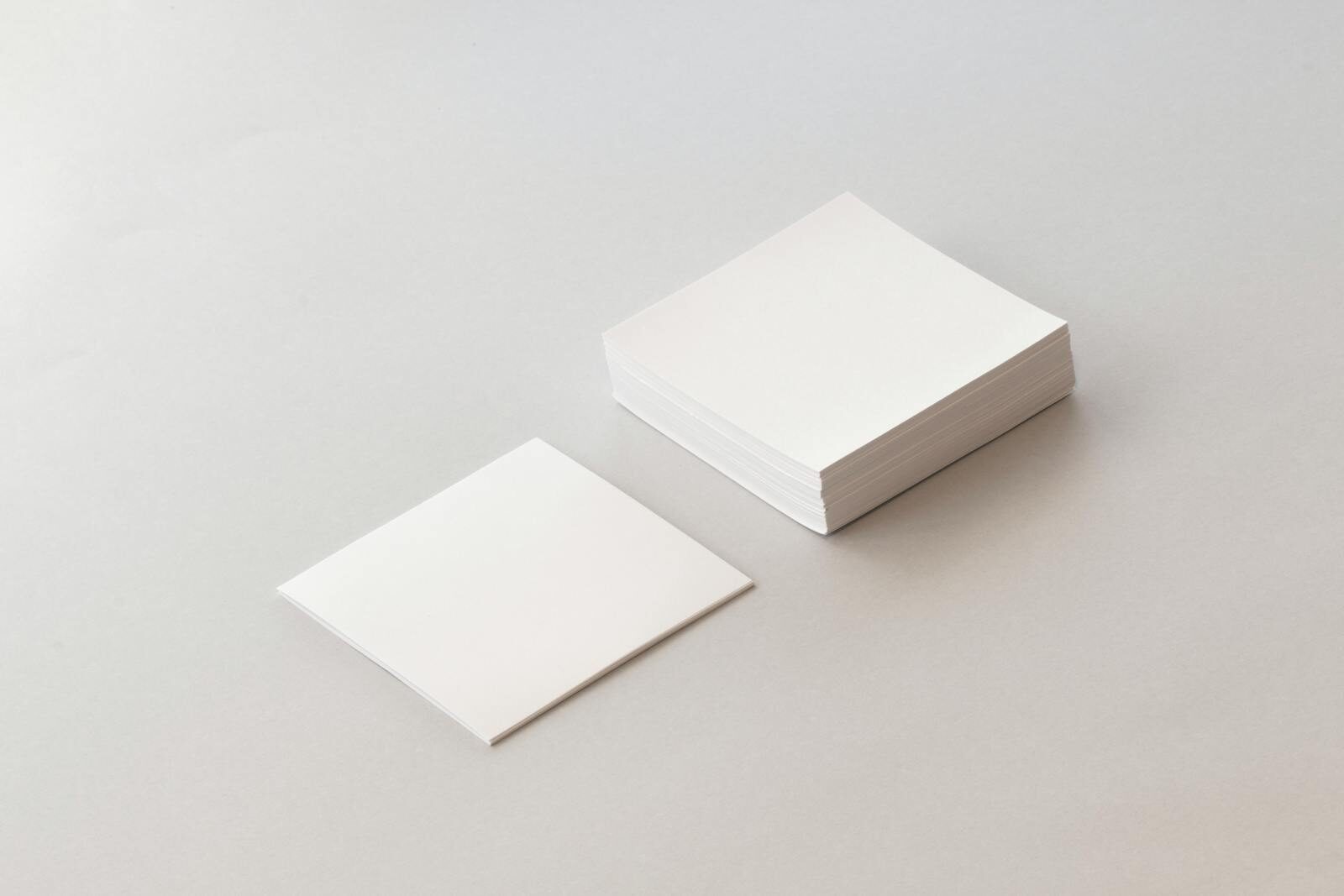 A minimalist image of a stack of blank paper with a single sheet on a neutral background, perfect for creative design and mockups.